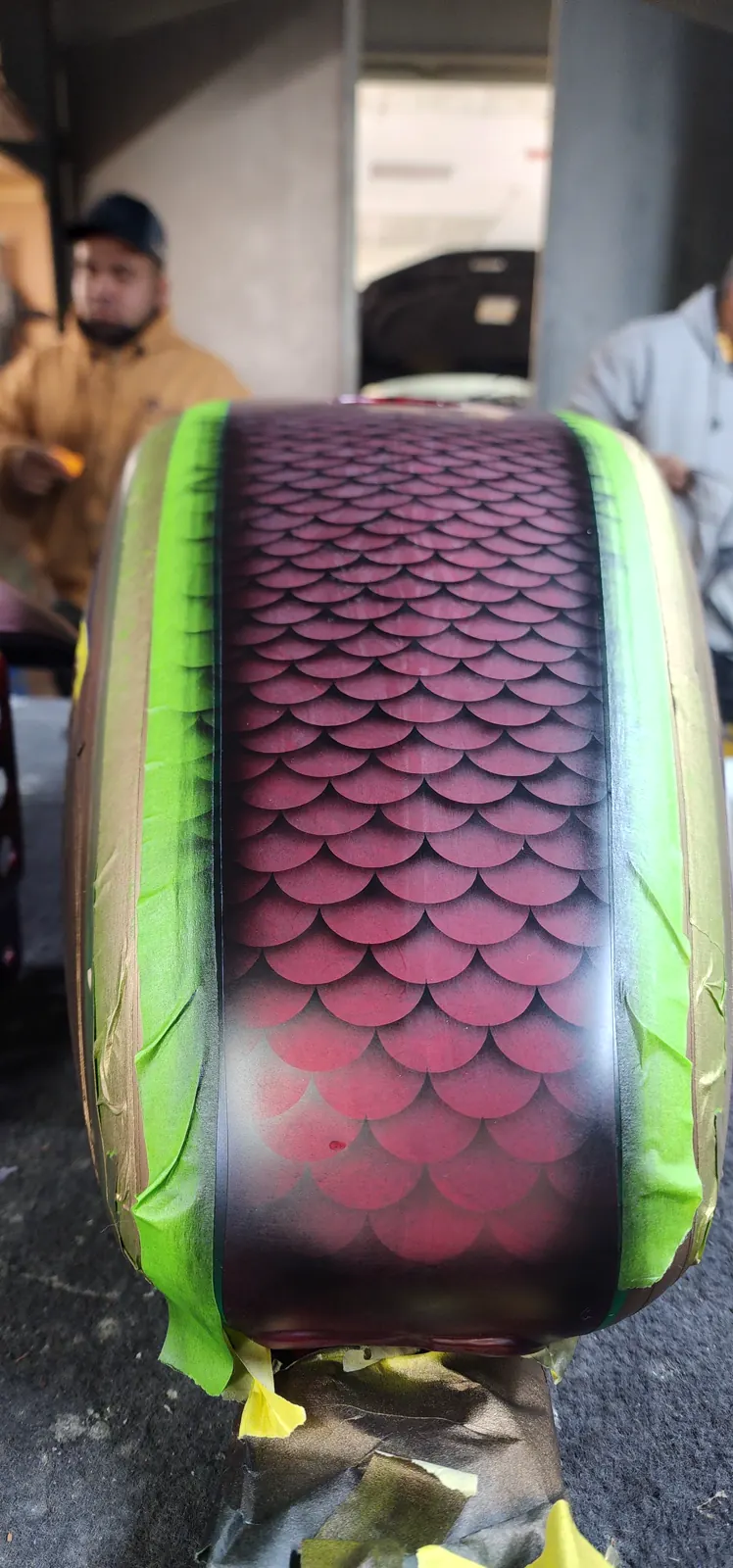 custom paint Sandy Springs airbrush — head-on close-up of a red dragon-scale fuel tank with masking tape still applied