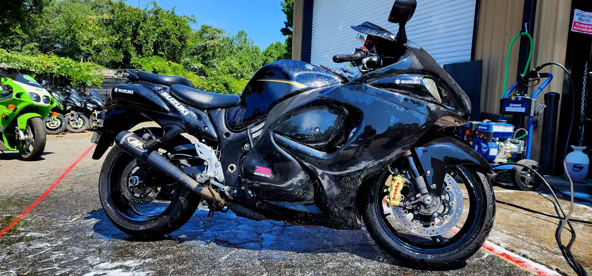 black Suzuki Hayabusa mid-wash outside the shop bay near Dallas GA, pressure washer and hose reel to the side