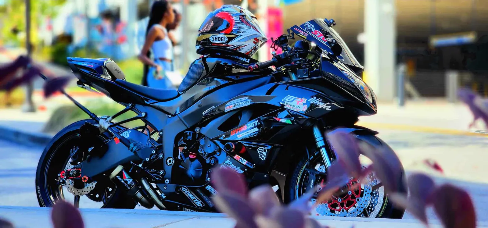 Custom paint Dallas GA — blacked-out Kawasaki Ninja ZX-6R with a Shoei helmet on the tail in the sun