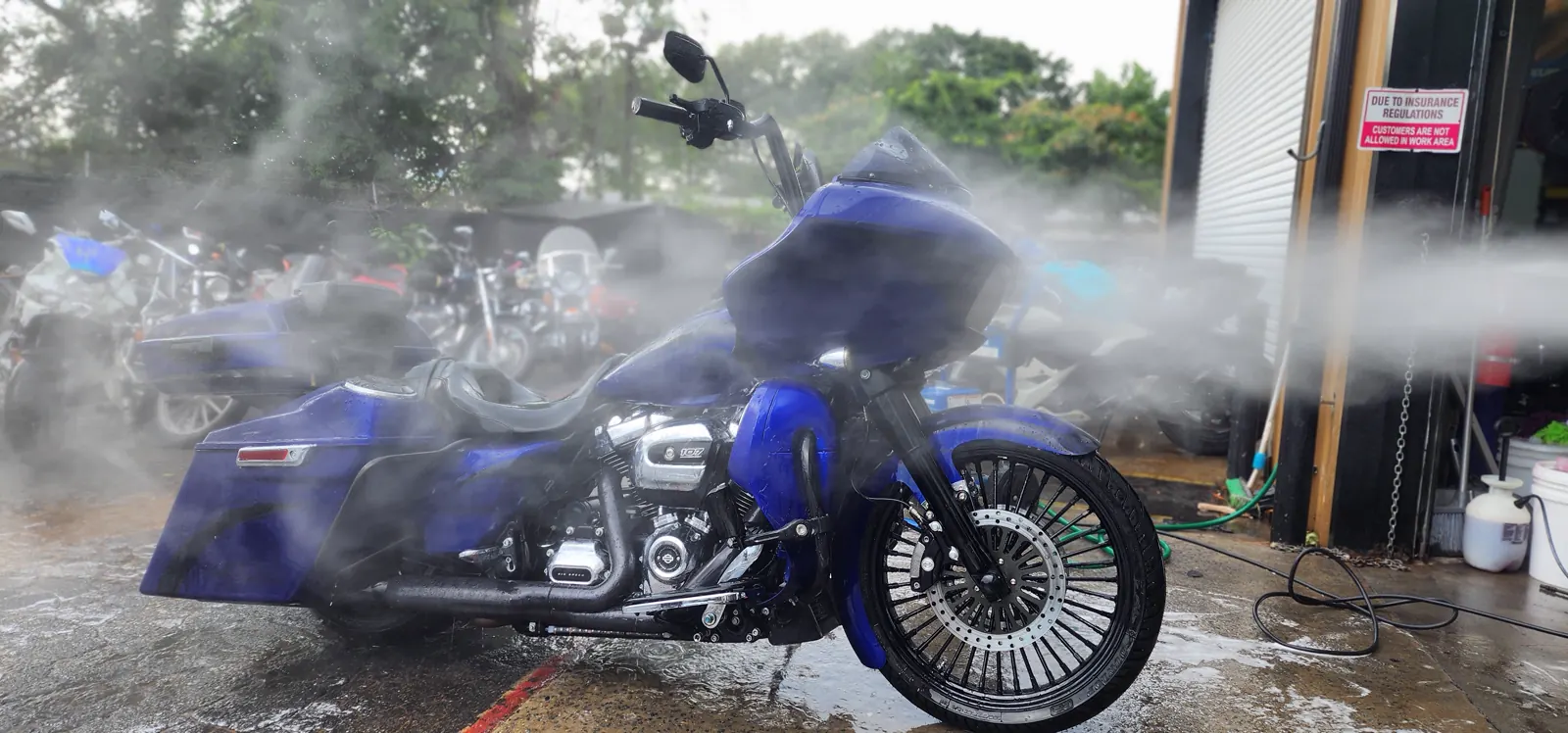 Custom paint Dallas GA — blue Harley Road Glide getting pressure-washed outside the shop