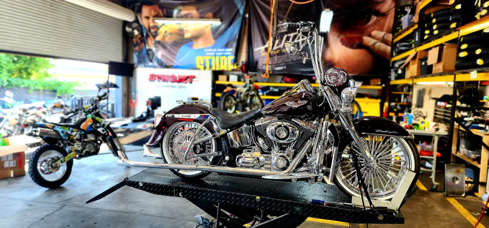 Faded paint fix Douglasville — burgundy Harley Softail Deluxe with chrome and spoked wheels on a lift
