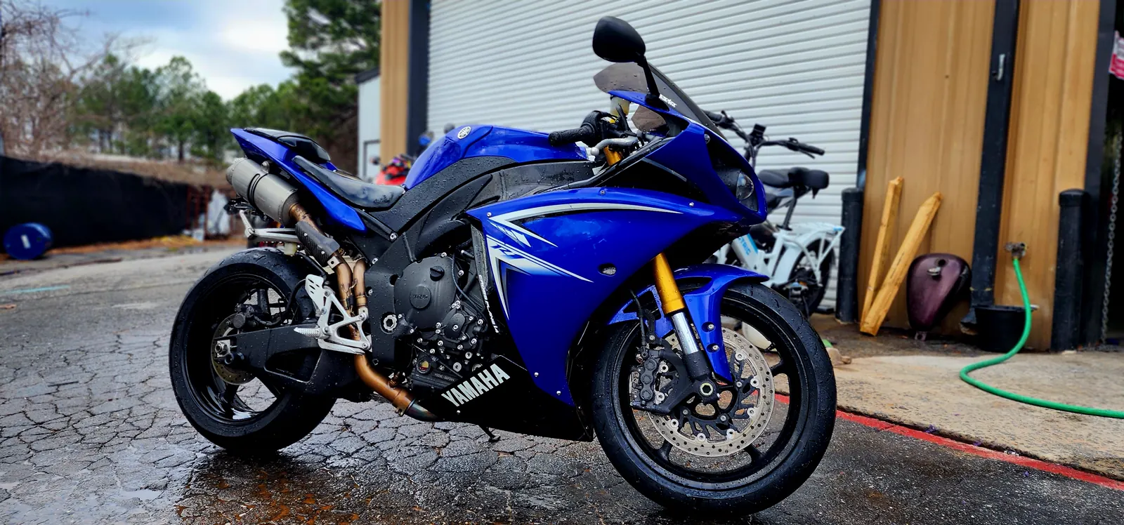 Fresh motorcycle paint Douglasville — clean blue Yamaha YZF-R1 with gold forks outside the shop bay
