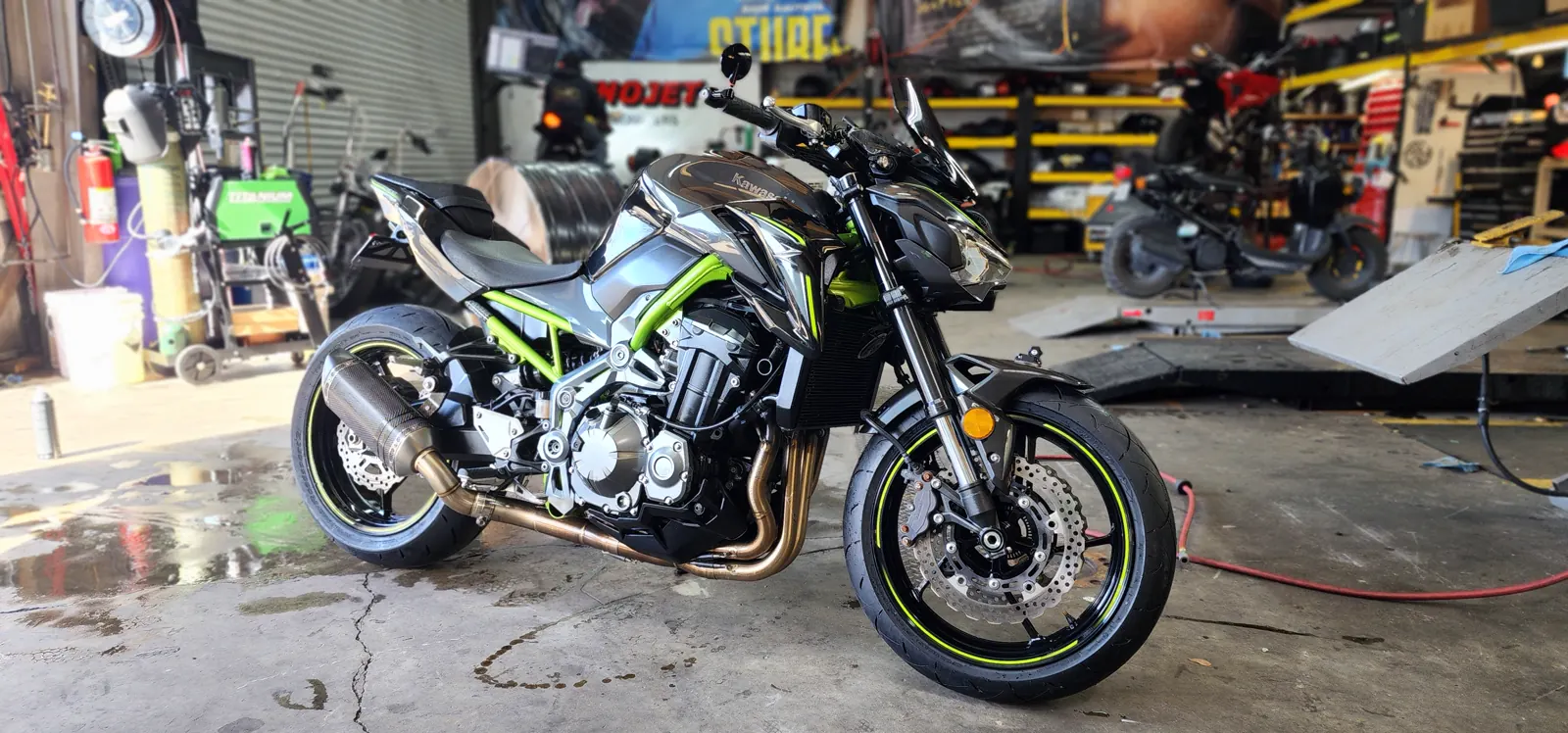 custom paint cost Douglasville — clean Kawasaki Z900 naked bike with green trim on the shop floor by the dyno