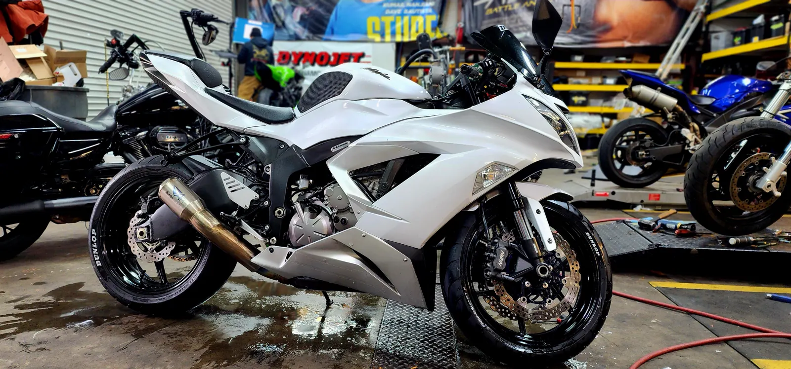 Custom paint Sandy Springs — pearl white Kawasaki Ninja ZX-6R with polished exhaust on a wet shop floor