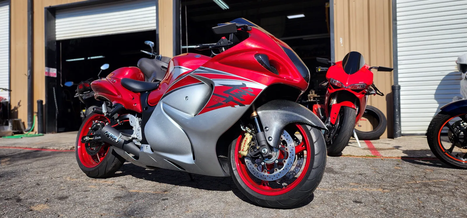 Custom paint work Roswell — red and silver Suzuki Hayabusa with red wheels and a carbon fender in the sun.