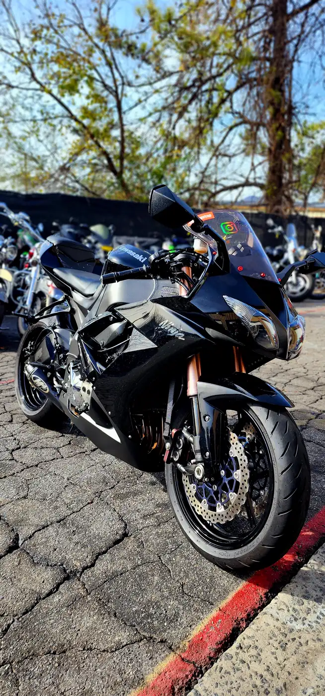 gloss paint Atlanta — glossy black Kawasaki Ninja with gold forks and chrome headlights lit by sunlight