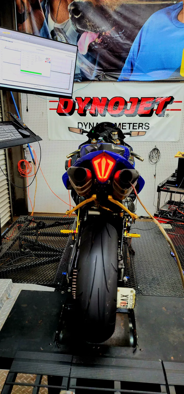 dyno tune vs stock — blue Yamaha R6 strapped on the dyno with twin exhausts and a tuning graph on the monitor