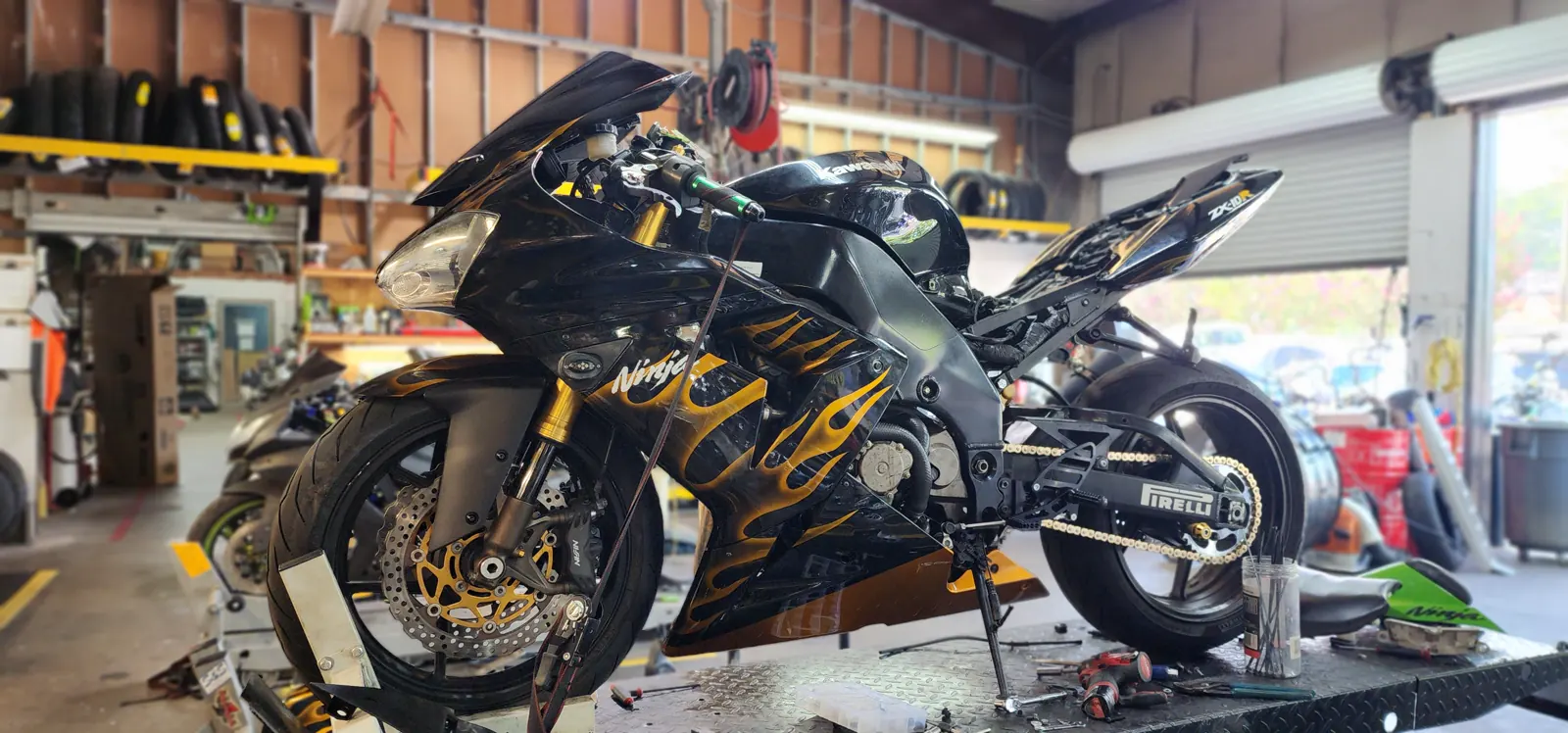 motorcycle maintenance Roswell — black Kawasaki Ninja ZX on a lift, rear wheel raised, gold chain and sprocket exposed