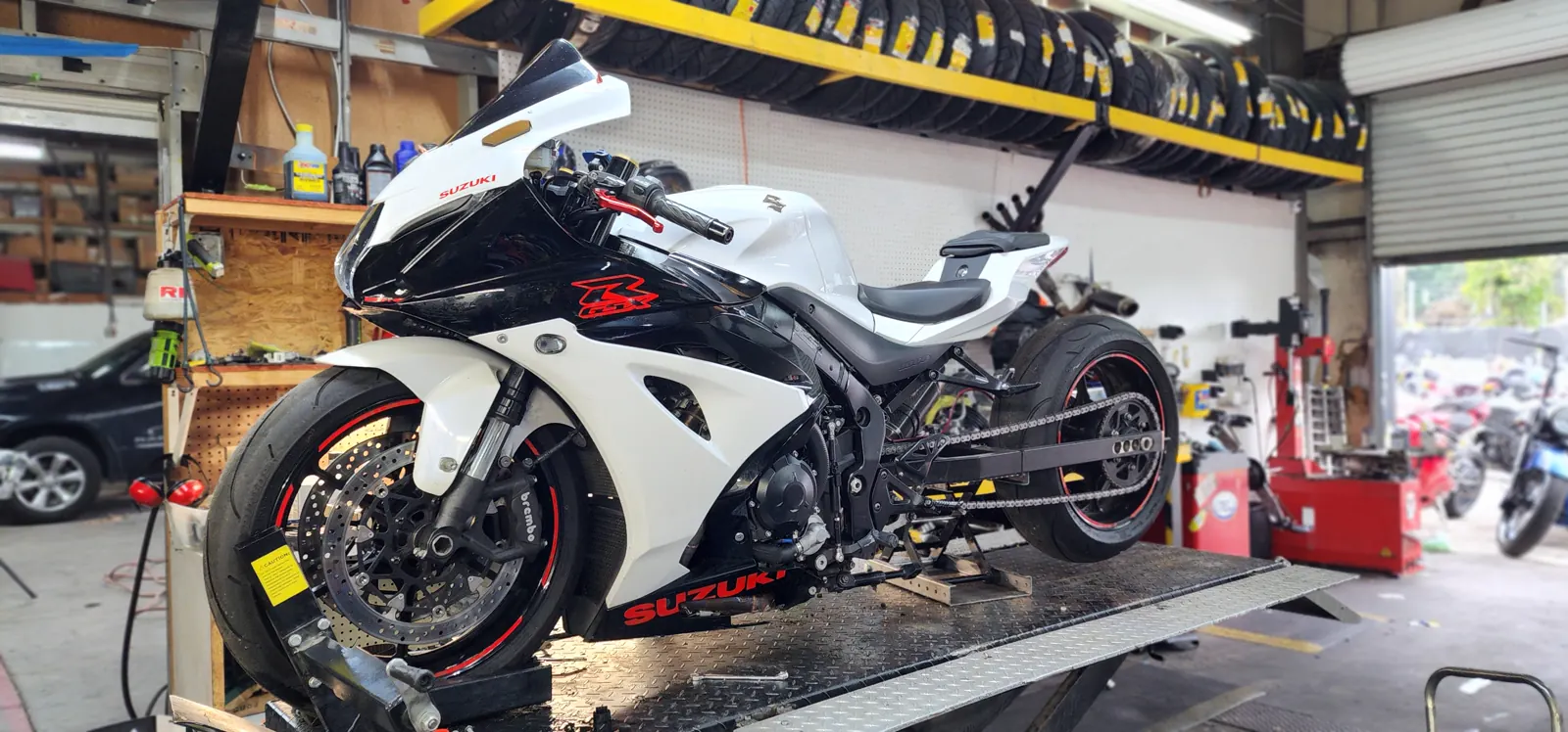 motorcycle service cost Newnan explained — white and black Suzuki GSX-R on a lift with exposed gold chain and rear sprocket