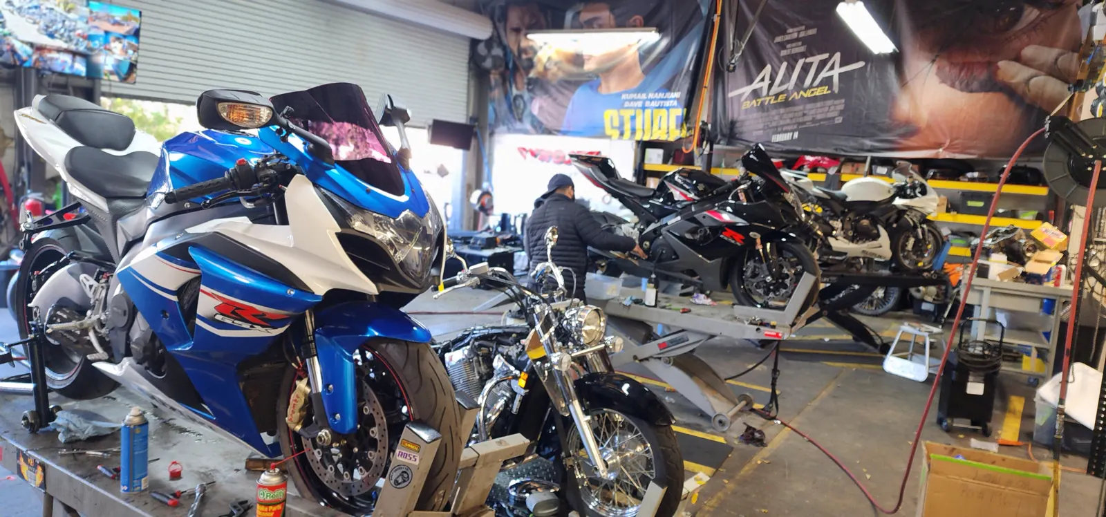 Dyno tuning near Cartersville — busy shop floor with a blue and white Suzuki GSX-R on a lift and a chrome cruiser mid-frame.