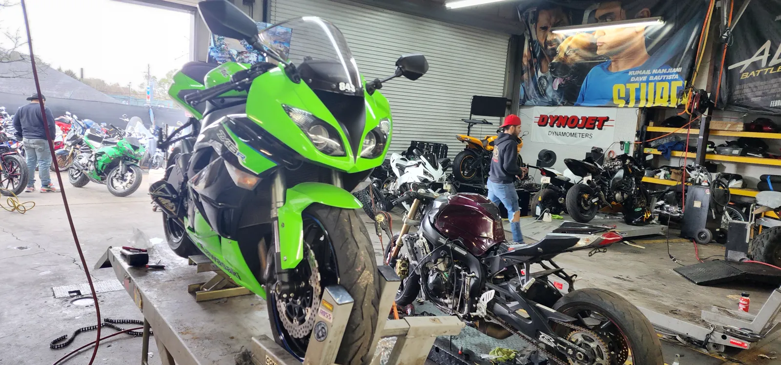 Motorcycle service Gainesville riders trust — green Kawasaki ZX-6R on a lift beside a stripped maroon sportbike