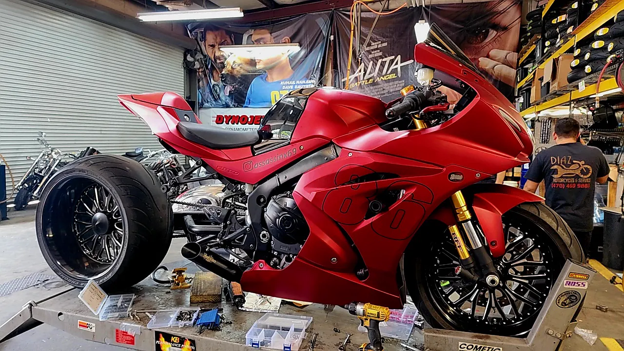 East Cobb overdue service — technician in a Diaz shirt working on a matte red Suzuki GSX-R with a wide rear wheel installed