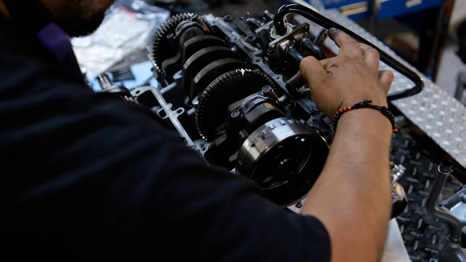 Motorcycle service for Mableton riders — technician's hands on a bare engine bottom end, crankshaft and flywheel visible.