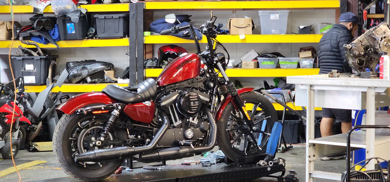 Indie service near Sandy Springs — red Harley Sportster Iron 883 on a lift, disassembled engine case on the bench behind