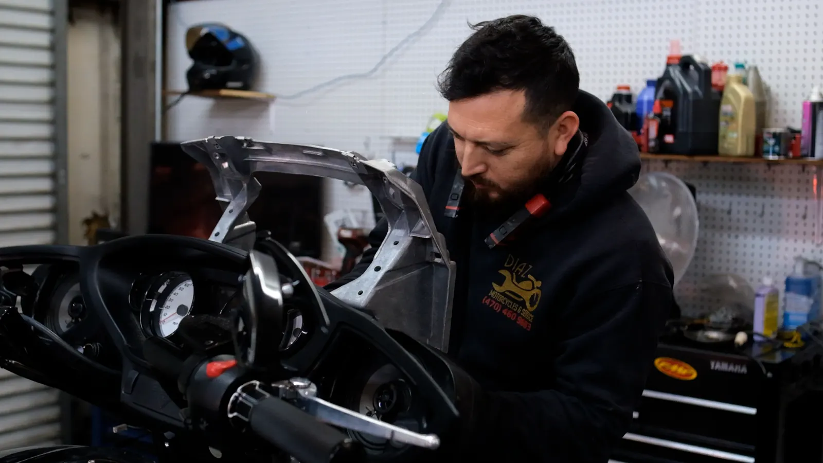 indie motorcycle service Kennesaw — technician fitting a fairing bracket above a touring bike's instrument cluster