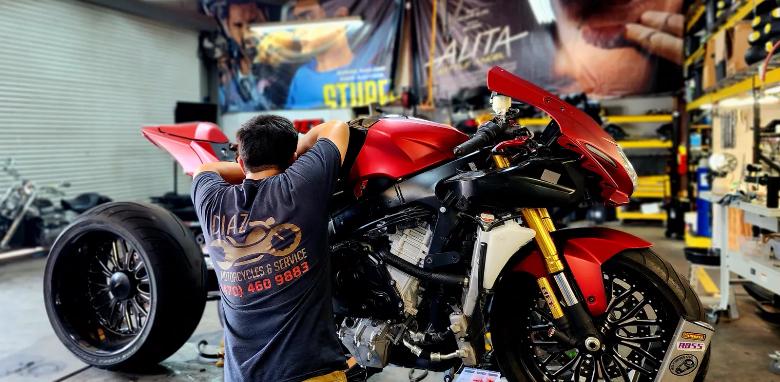 dealer vs indie service Kennesaw — technician leaning over a red naked sportbike with exposed frame and gold forks