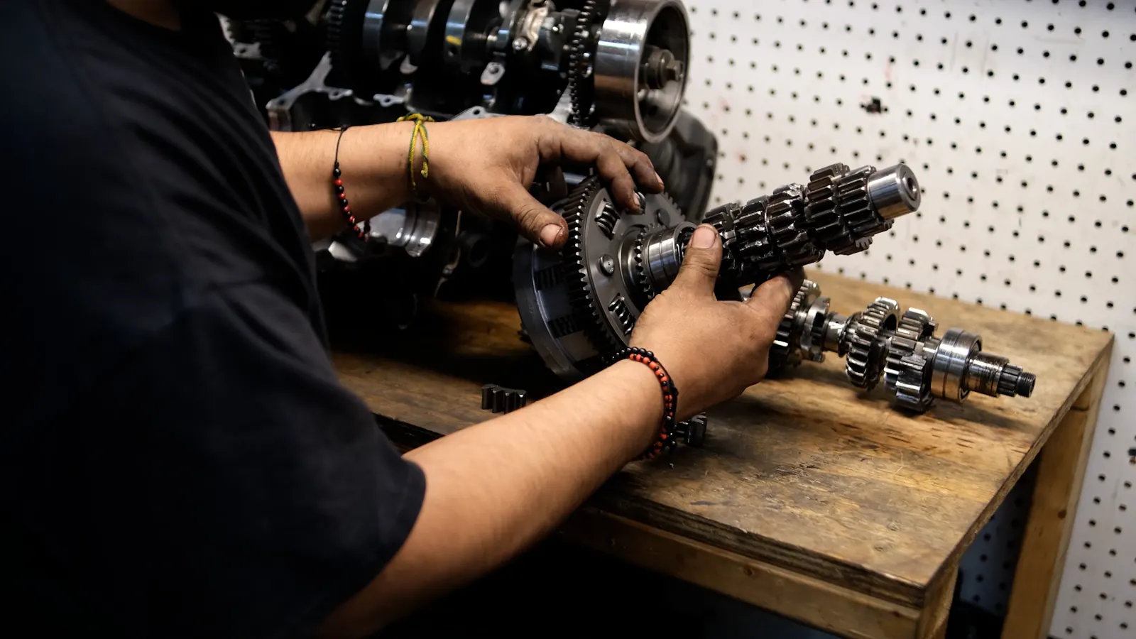 engine work behind good motorcycle service Lawrenceville — technician holding a transmission gear shaft and clutch basket