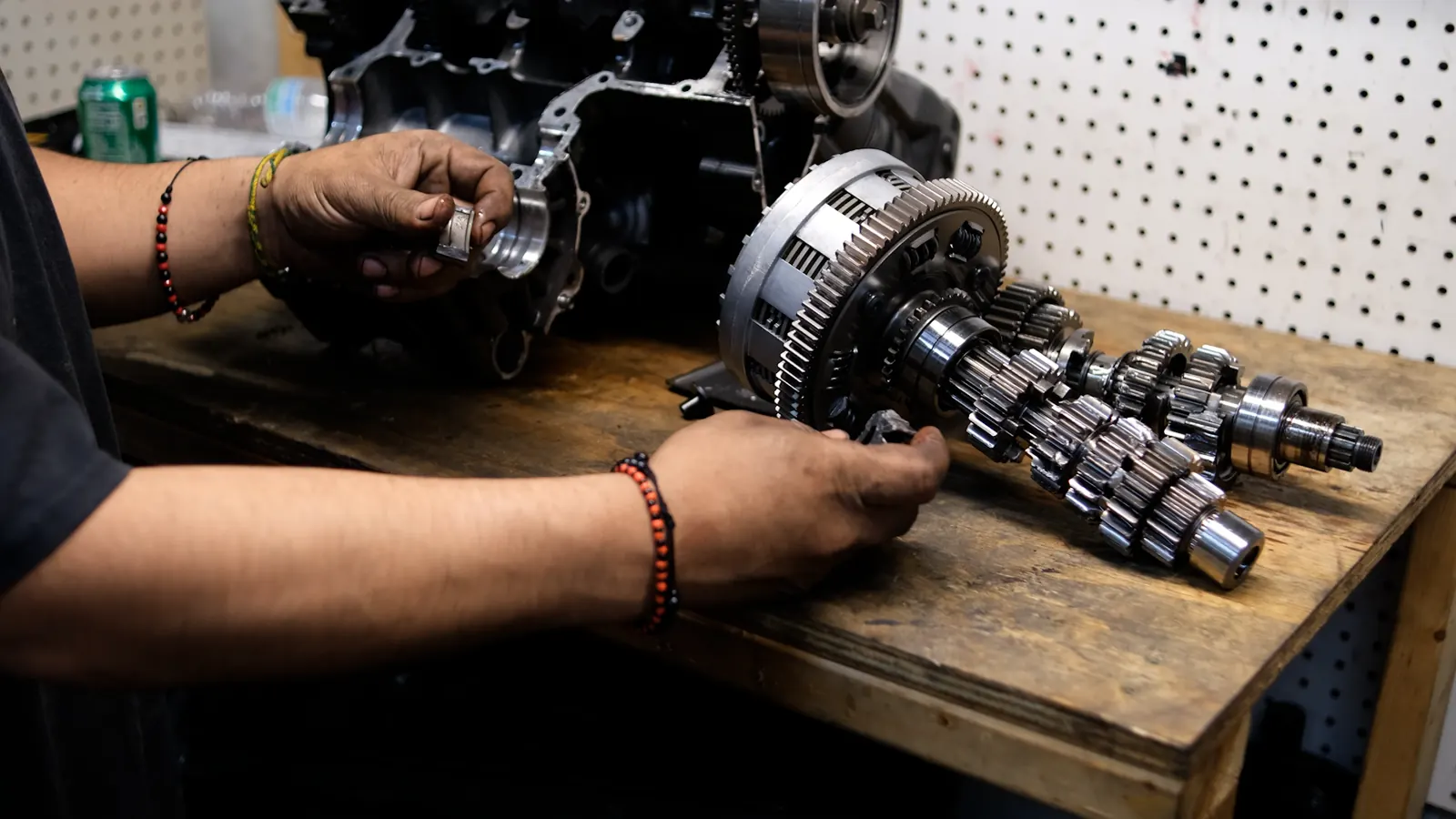 motorcycle repair Dallas GA — hands holding a shift component beside a disassembled transmission and clutch basket