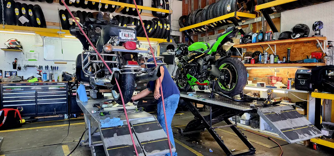 Bike service for Newnan riders — technician working on a black cruiser beside a green Kawasaki sportbike