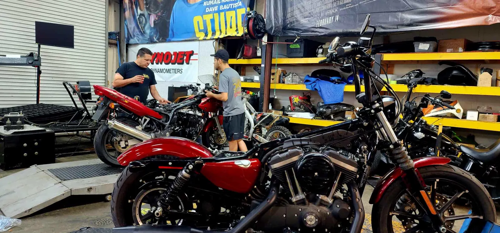 Motorcycle service Smyrna GA — two techs work on a red naked bike with the tank lifted, a red Iron 883 in front.