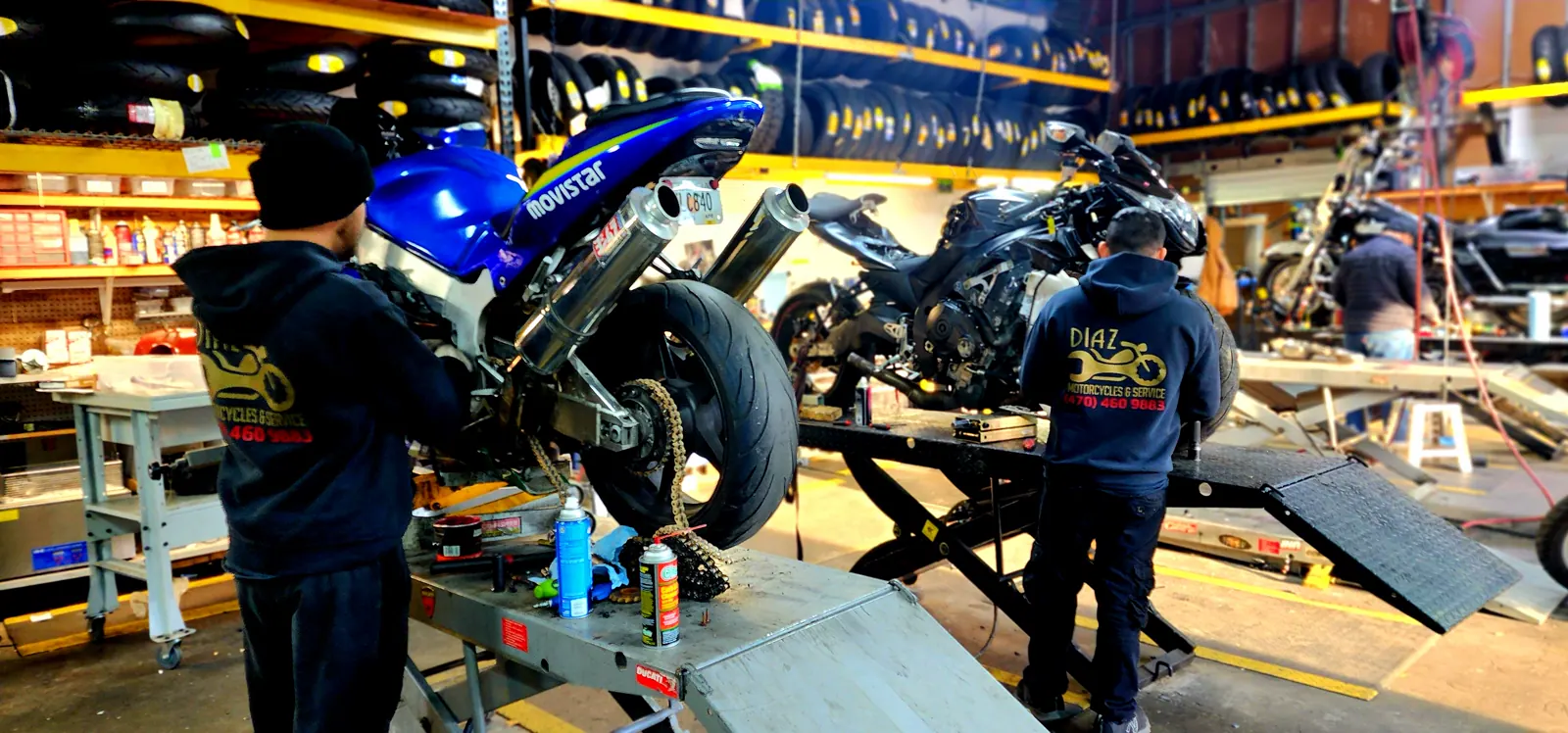 Motorcycle repair Acworth riders drive for — two Diaz techs working on bikes on lifts, rear wheel and chain exposed