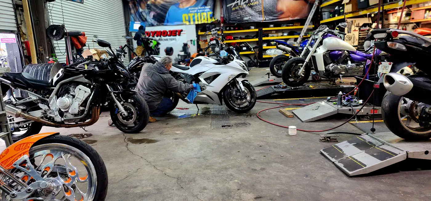 Overdue motorcycle service Roswell — wide view of the shop floor with a tech working on a white sportbike and bikes on lifts