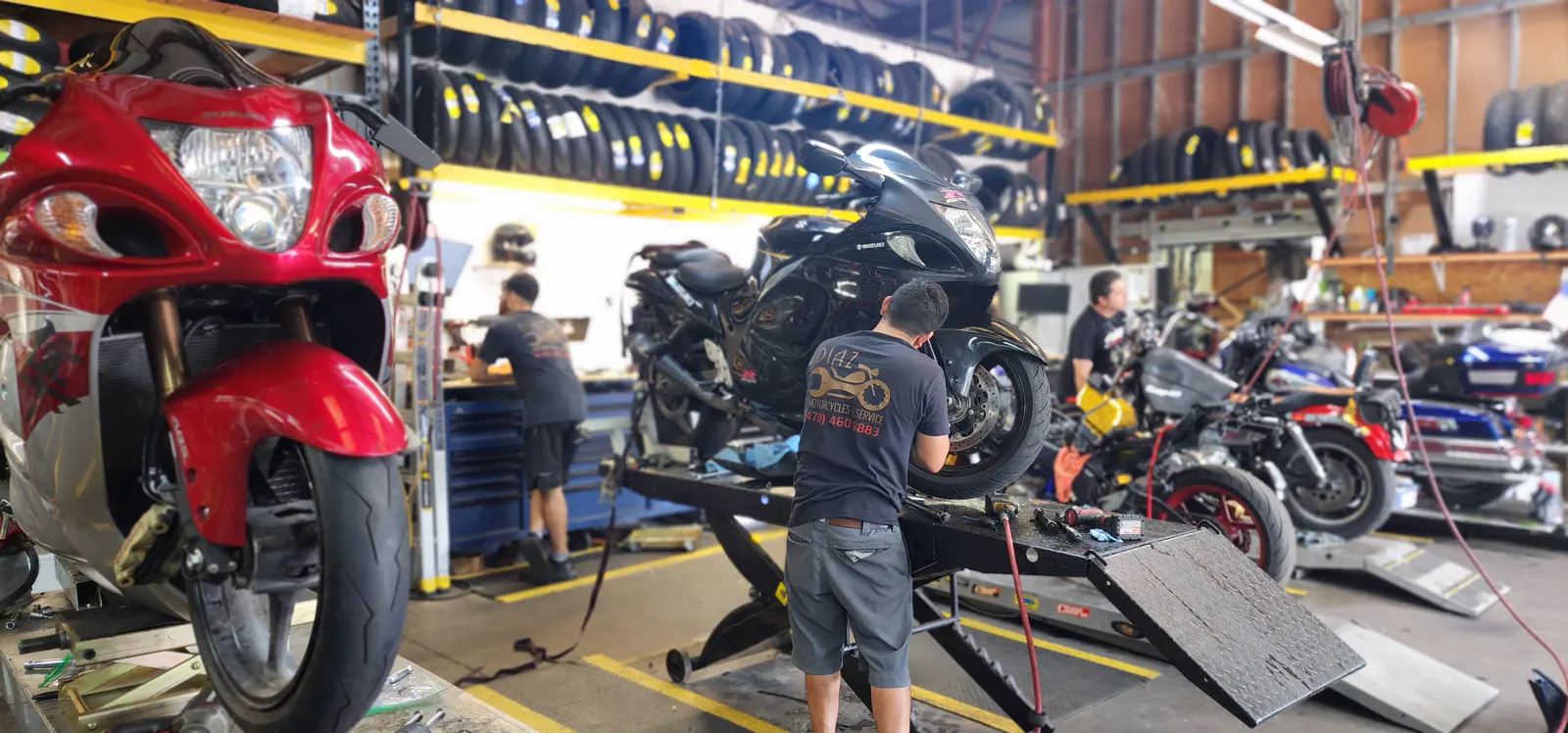 Independent motorcycle shop Acworth trusts — red Hayabusa on a lift and a Diaz tech working on a black Hayabusa behind