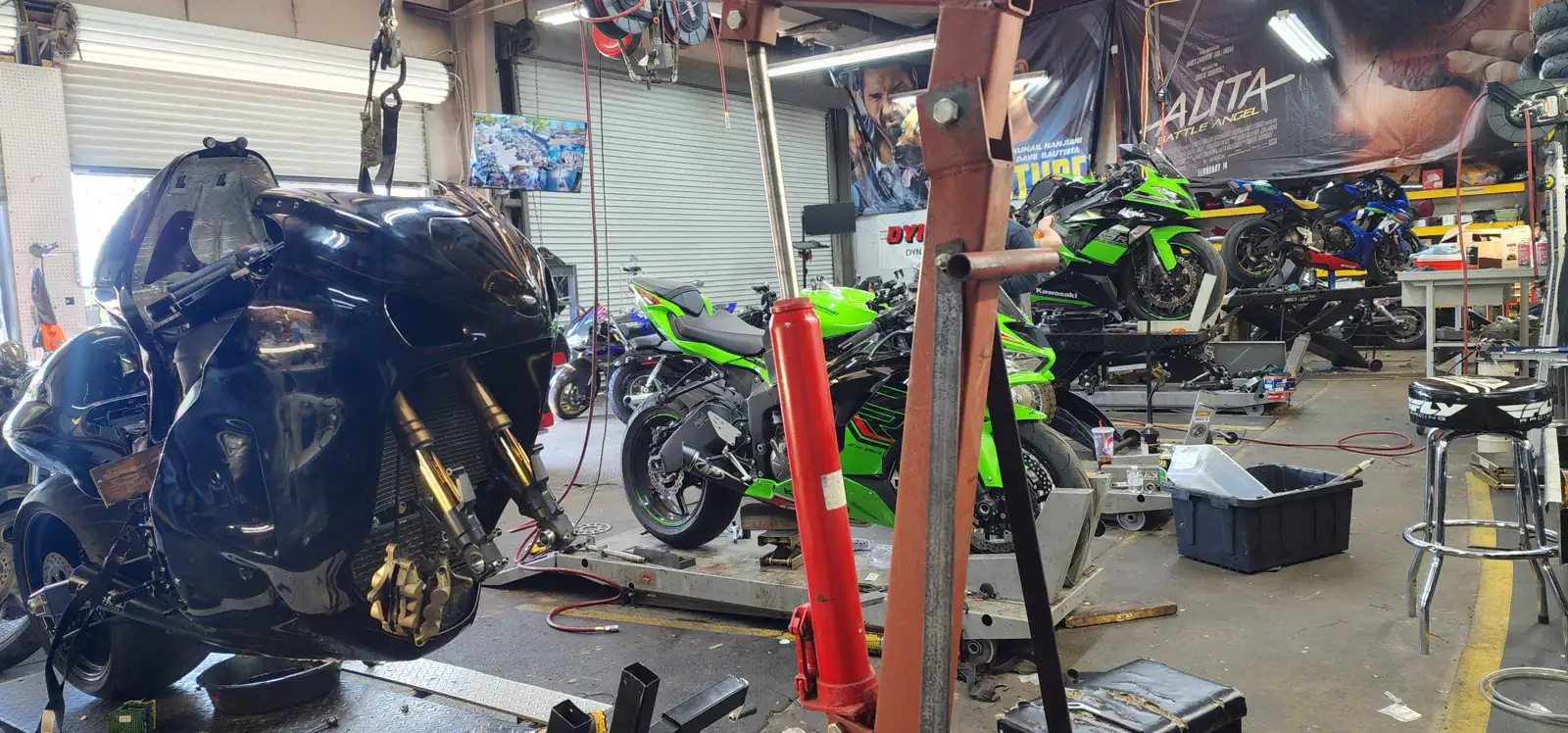 Motorcycle service Roswell — black Hayabusa hoisted with bodywork off and gold forks exposed in the shop