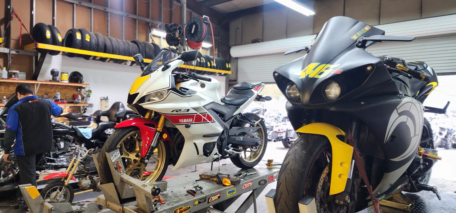 Motorcycle service near Cartersville — Yamaha R3 in heritage livery and a VR46-liveried R1 on lifts inside the shop