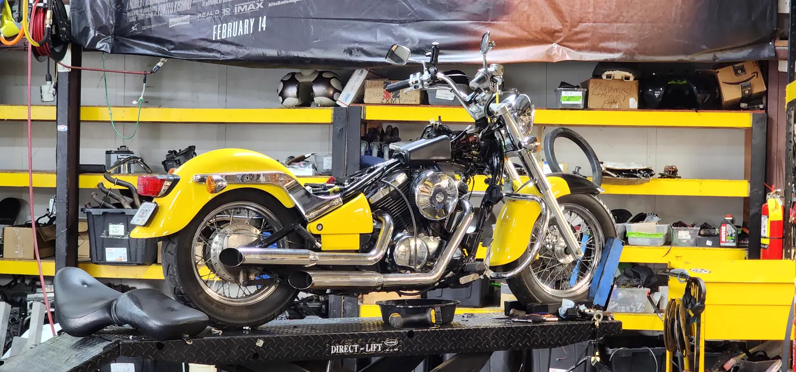 indie motorcycle service Roswell — yellow Honda Shadow-style cruiser on a lift with a drain pan underneath