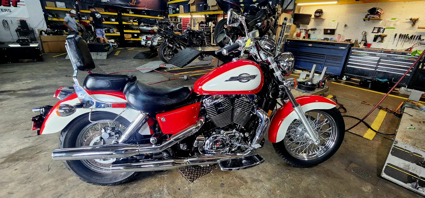 motorcycle restoration Smyrna — red and white Honda Shadow Aero cruiser with chrome spoked wheels on the shop floor