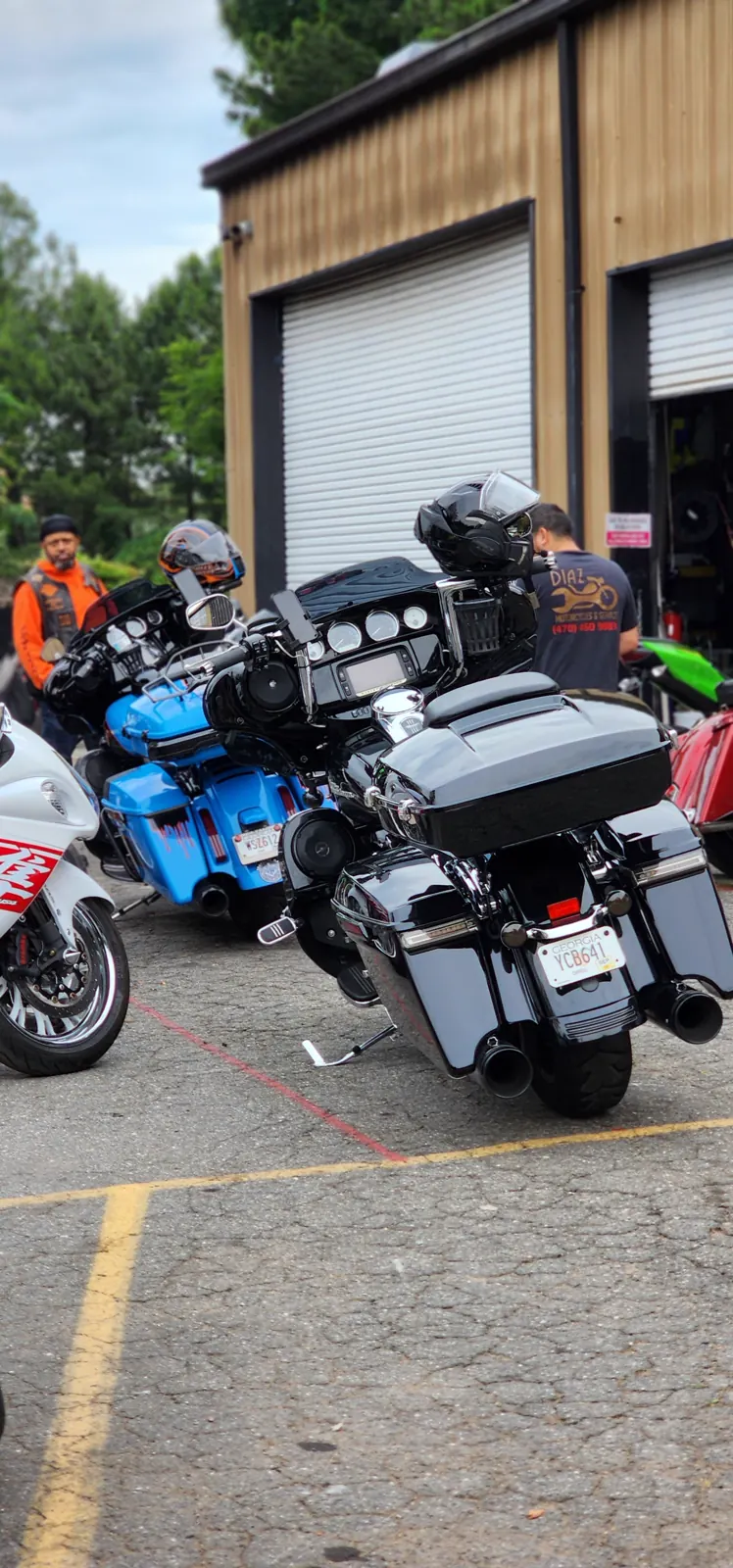 motorcycle transport Canton — bagger lineup outside the shop with a Diaz staffer at the bay door and a customer in an orange vest