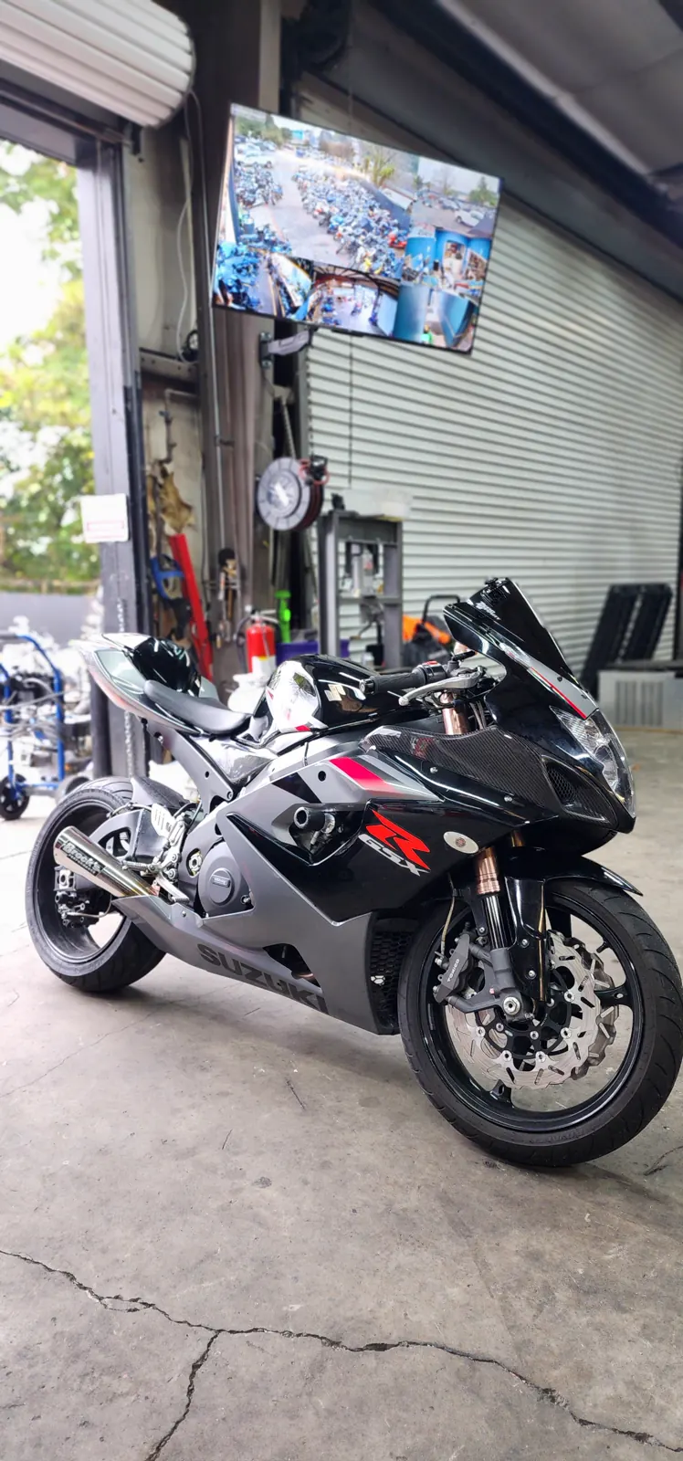 Dealer vs indie service Marietta — black and silver Suzuki GSX-R parked at the open shop bay door with tools inside