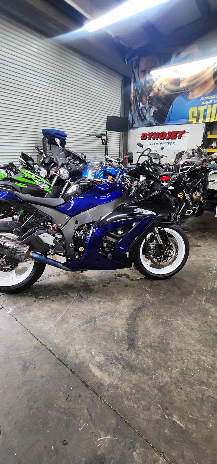Motorcycle transport Canton — blue and black Kawasaki ZX-10R with white wheels by the Dynojet banner