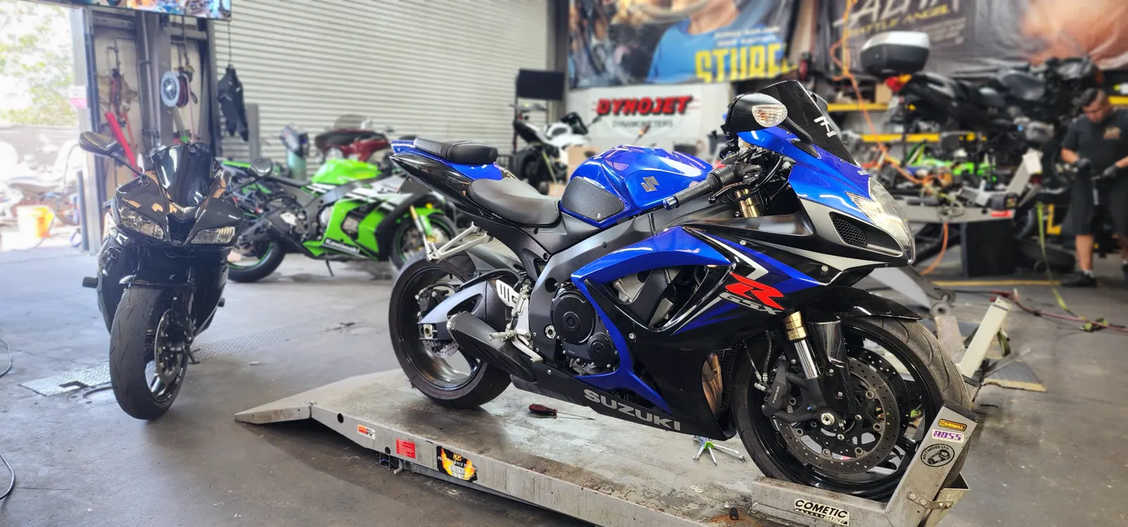 Motorcycle transport Canton — blue and black Suzuki GSX-R750 on an aluminum lift by the Dynojet banner