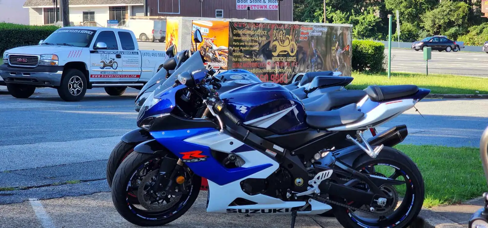 overdue service East Cobb — blue and white Suzuki GSX-R parked beside the branded Diaz service truck and trailer