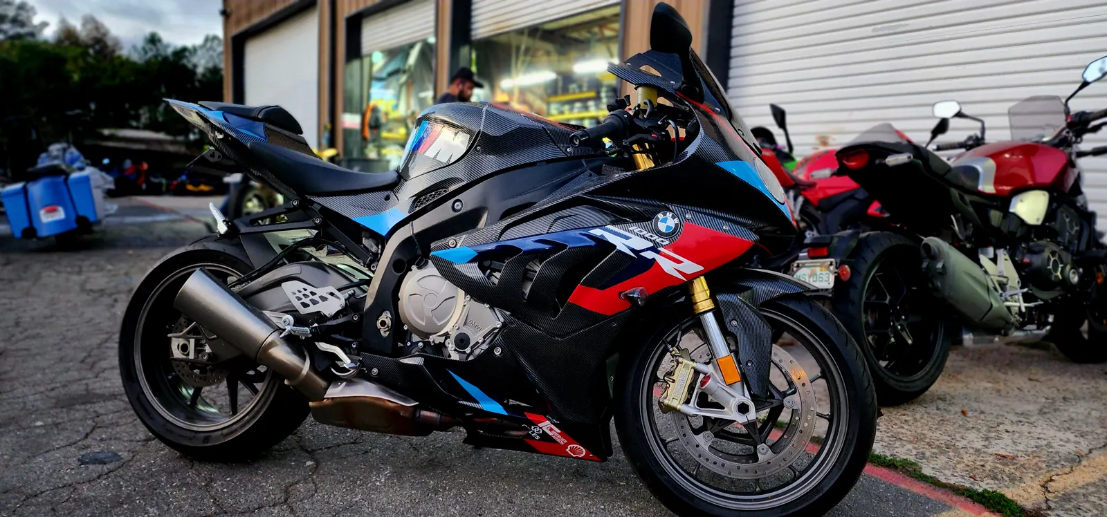 overdue service East Cobb — BMW S1000RR in M motorsport livery with carbon bodywork parked outside the shop bay