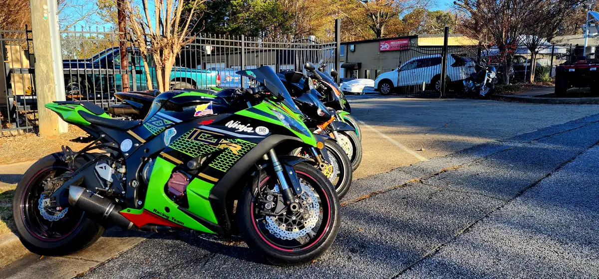 Motorcycle service near Sandy Springs — green KRT Kawasaki Ninja leading a row of sportbikes on the shop sidewalk