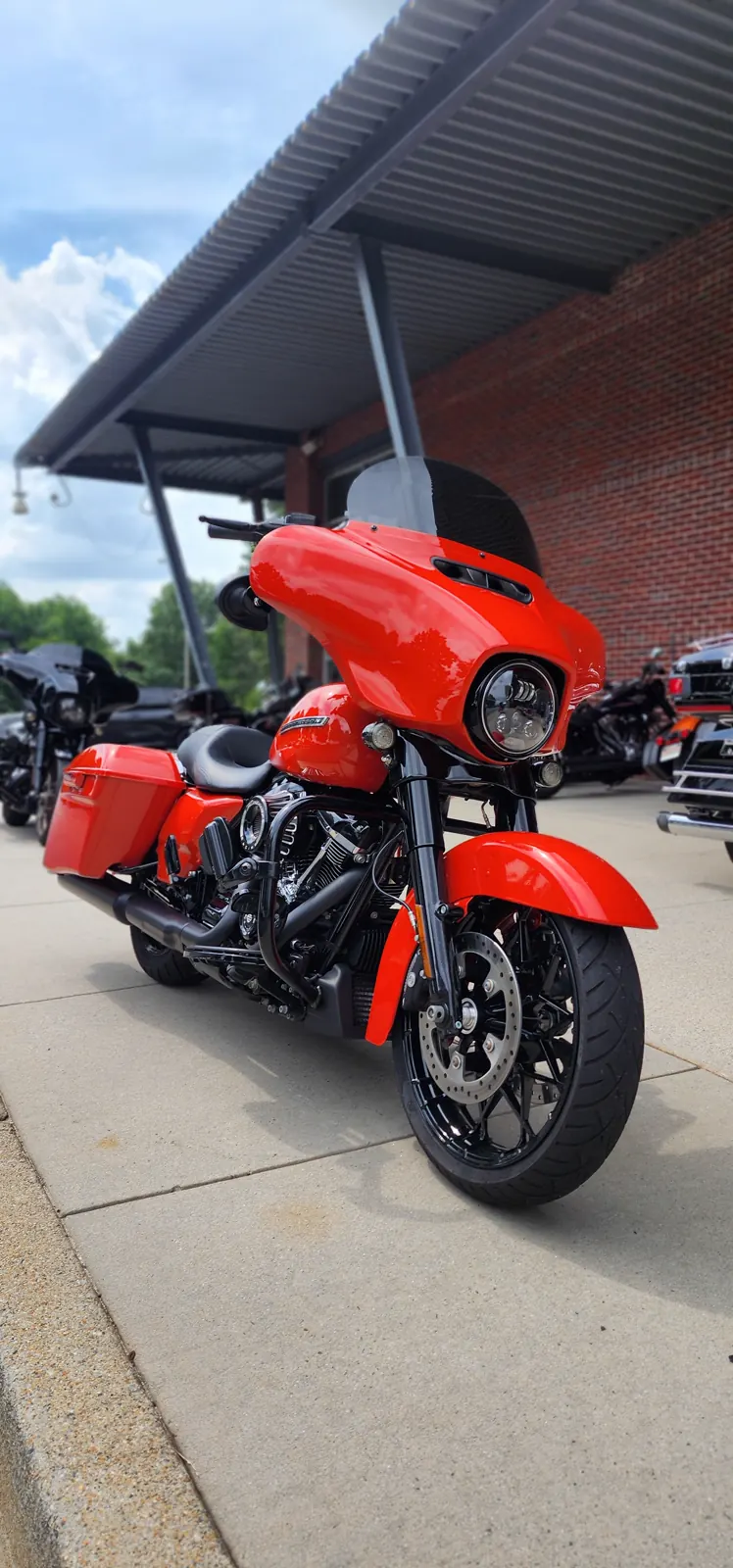Indie motorcycle service for Sandy Springs riders — orange Harley Street Glide with black wheels parked under a metal canopy