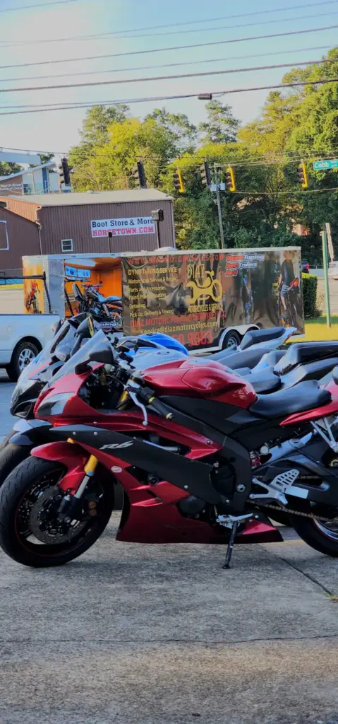Three sport motorcycles are parked by a truck displaying a bold motorcycle-themed advertisement.