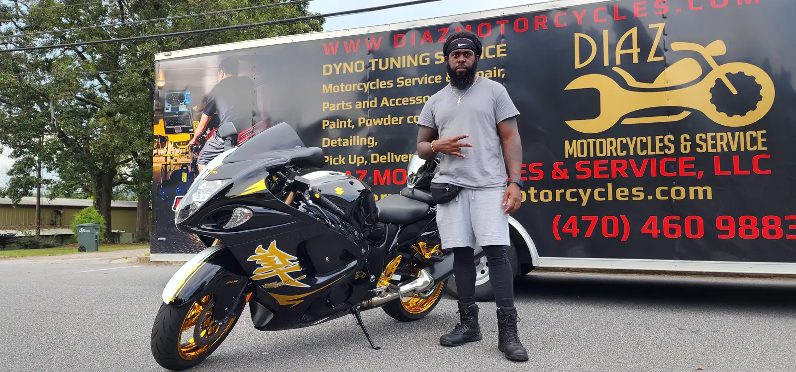 motorcycle transport East Cobb — customer posing by a black-and-gold Hayabusa at the branded Diaz trailer