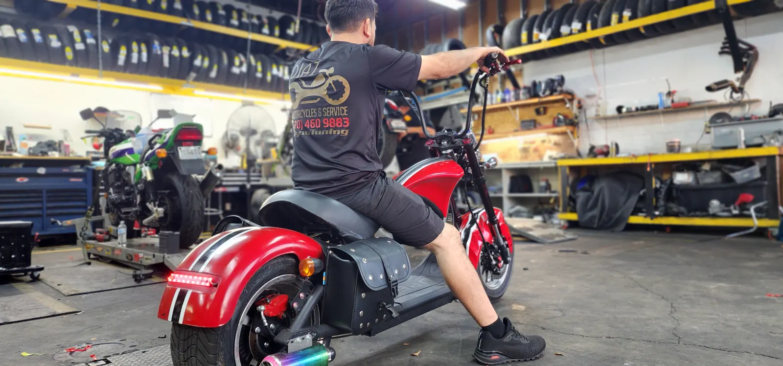 motorcycle transport cost Roswell — Diaz staffer seated on a red fat-tire electric chopper scooter inside the shop