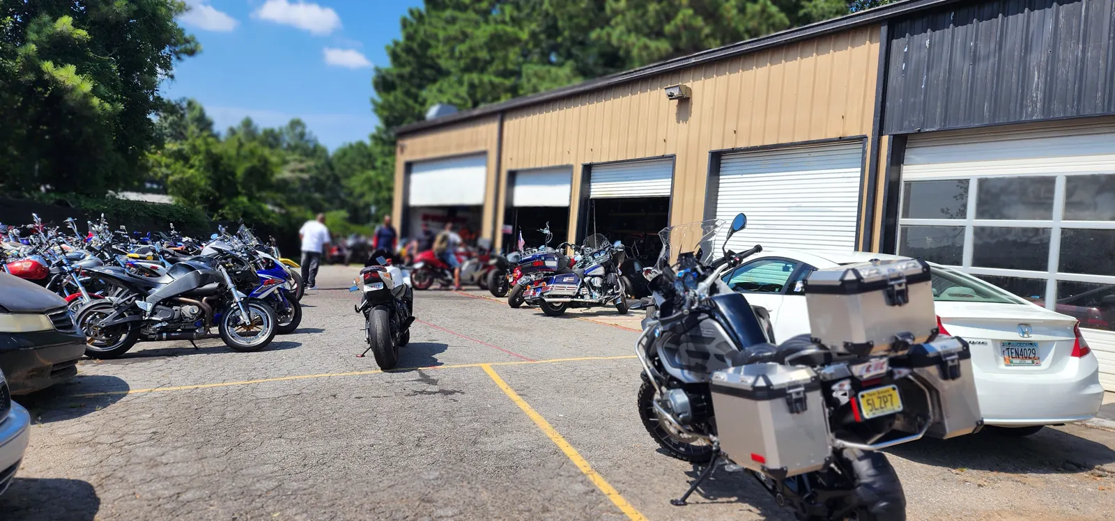 enclosed vs open transport Roswell — tan metal Diaz shop with roll-up bays and a BMW GS adventure bike out front