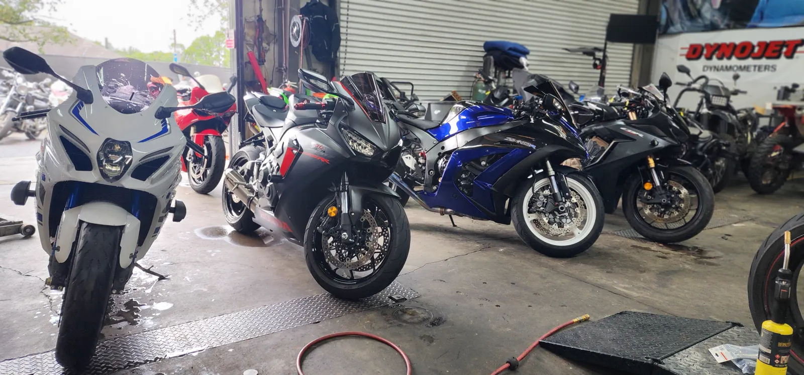 motorcycle transport Roswell — sportbikes on the wet shop floor by the bay door with a Dynojet banner