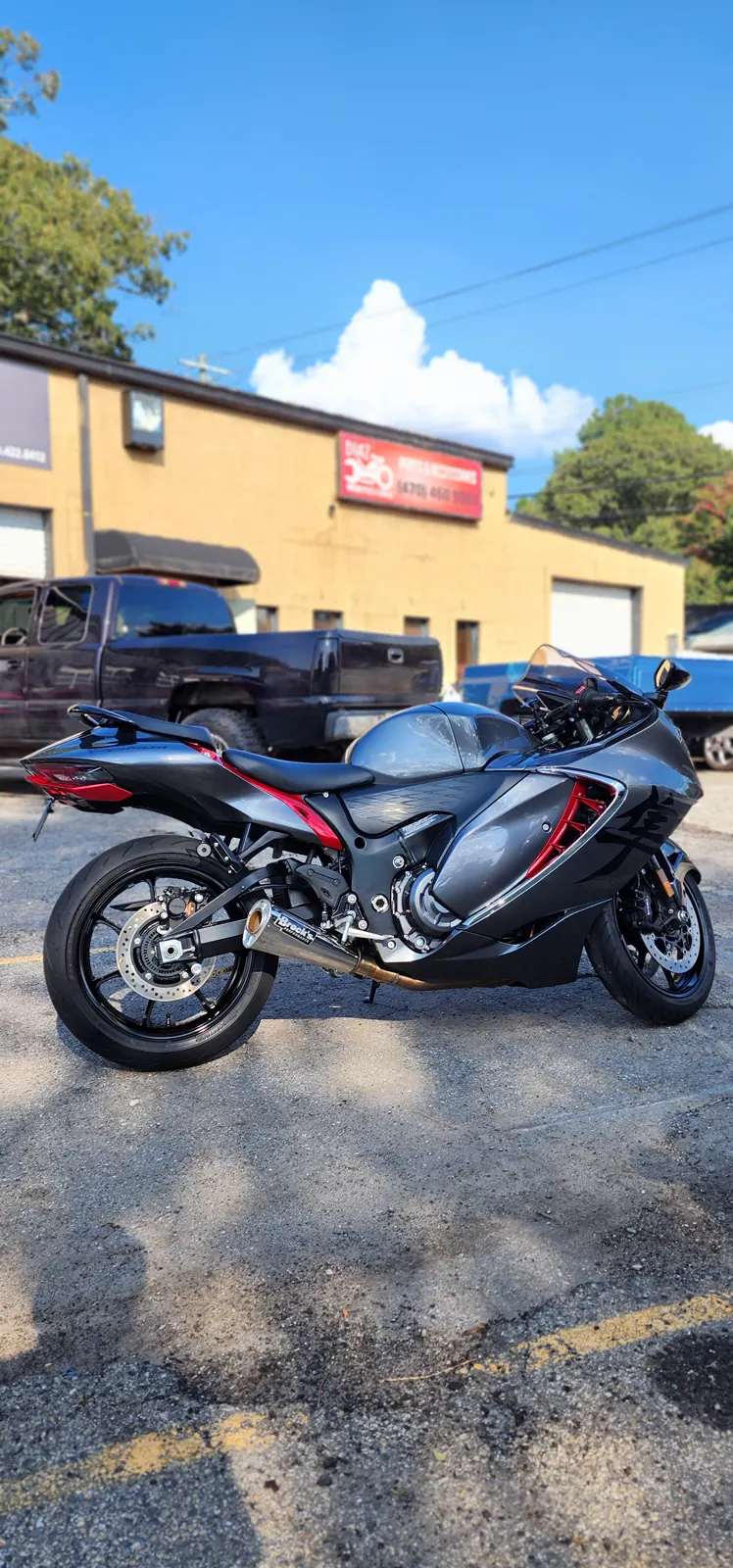 Dealer vs indie service Dallas GA — gray and red Suzuki Hayabusa with Brock's exhaust outside the Diaz storefront