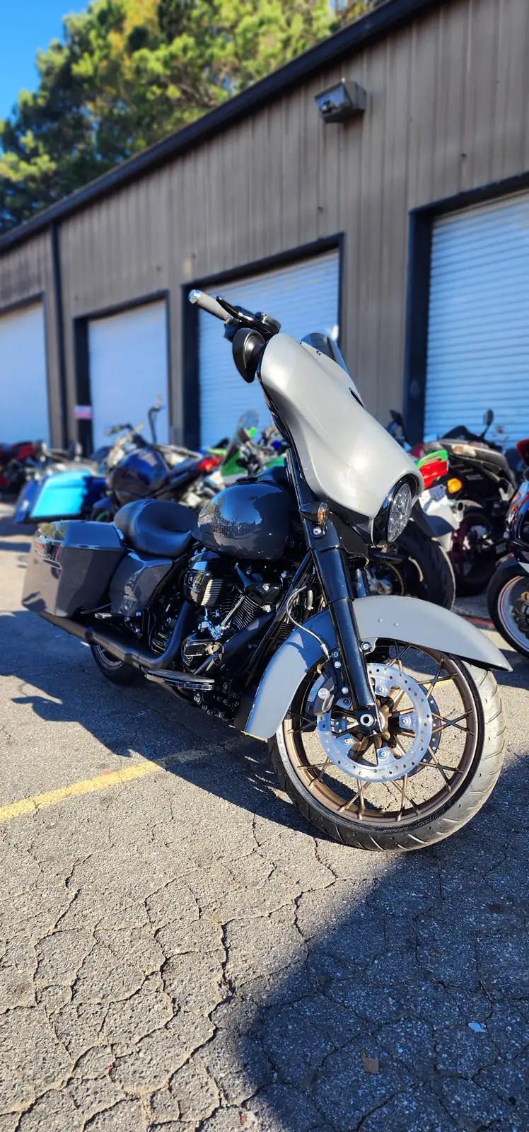 overdue service caught up — grey and black Harley-Davidson Street Glide with bronze wheels outside the Diaz roll-up doors