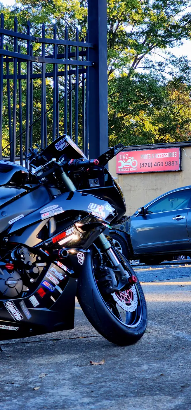 motorcycle service Douglasville — sticker-covered black Kawasaki Ninja track bike beside the Diaz Parts sign