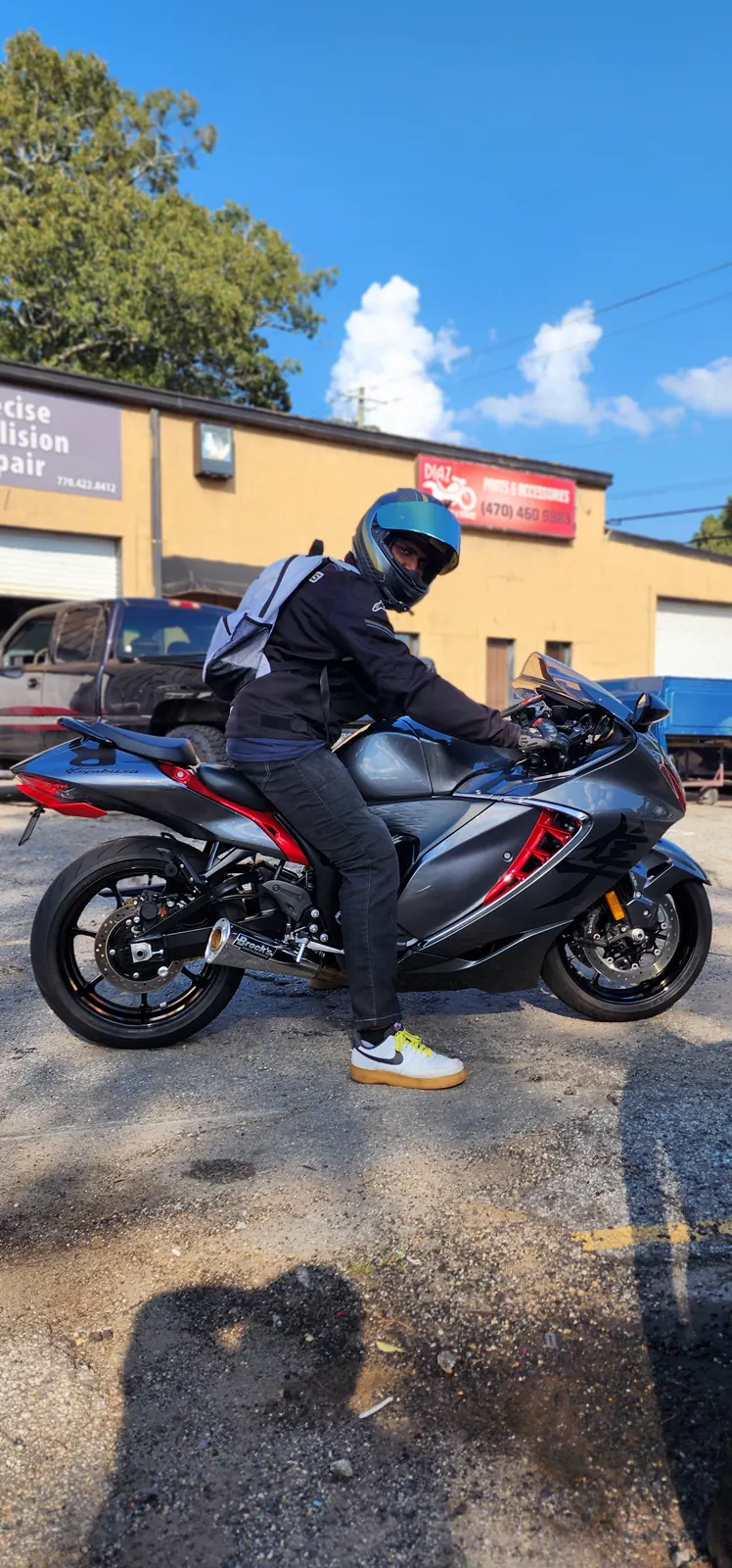 Independent motorcycle shop Acworth riders visit — helmeted rider with a backpack seated on a gray and red Hayabusa