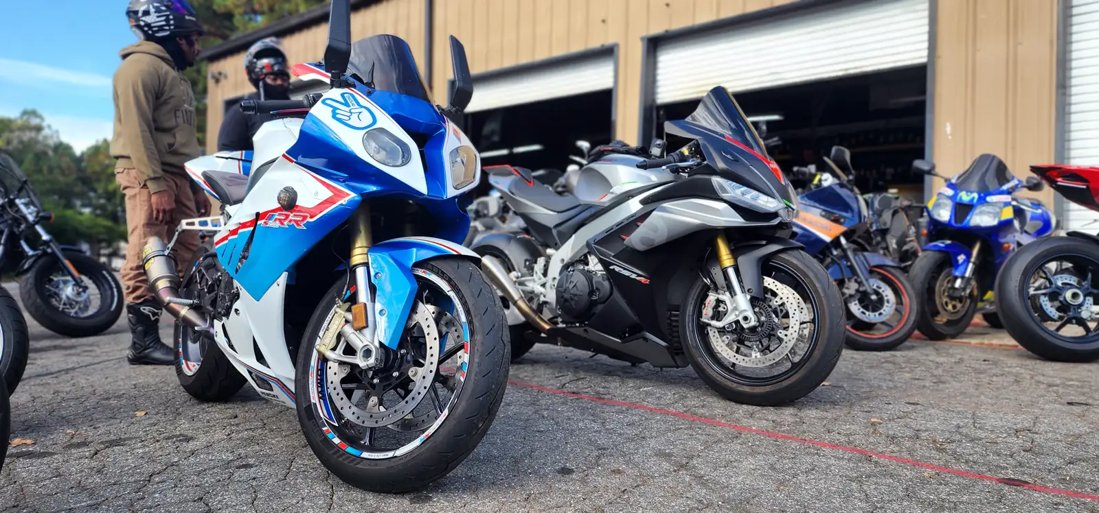 Overdue motorcycle service Cartersville — lineup of sportbikes outside the shop led by a blue and white Suzuki GSX-R and a silver Aprilia RSV4