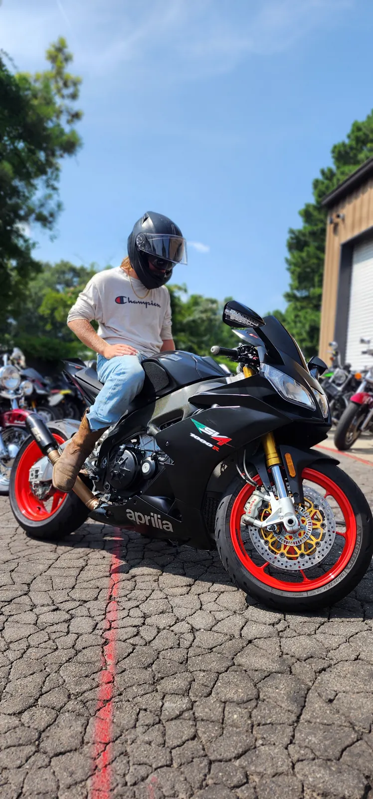 Enclosed vs open transport Smyrna — rider in a black helmet on a black Aprilia RSV4 with gold Brembo rotors in the shop lot